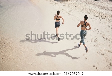 Leaving their mark on the track. High angle shot of two unrecognizable athletic young women out for a run on the beach.