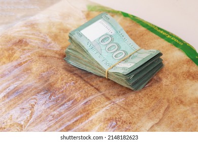 Lebanese bread next to Lebanese Lira money on a white background, bread crisis, wheat crisis, Lebanon, Beirut, Tripoli, Lebanese Lira, Dollar, Passport Crisis, Lebanese Crisis.