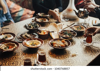 Lebanon Cuisine Served In Restaurant. A Young Company Of People Is Smoking A Hookah And Communicating In An Oriental Restaurant. Traditional Meze Lunch