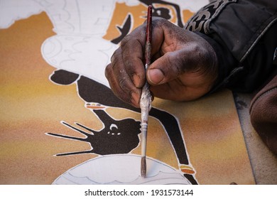 Lecce, Italy-March 7, 2021: Close-up Shot To A Black Hand With A Brush Of A Street Artist Painting Paintings With Colored Sand.