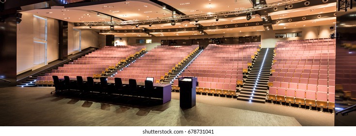 Lecture hall with red seats for thousand students. On the stage desks for teachers