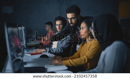 Lecturer Helps Scholar with Project, Advising on Their Work. Teacher Giving Lesson to Diverse Multiethnic Group of Female and Male Students in College Room, Teaching New Academic Skills on a Computer.