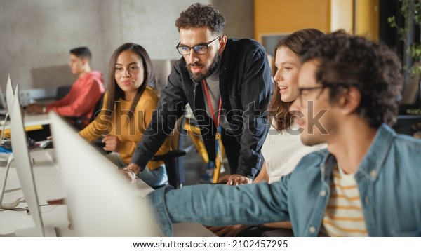 Lecturer Helps Scholar with Project, Advising\
on Their Work. Teacher Giving Lesson to Diverse Multiethnic Group\
of Female and Male Students in College Room, Teaching New Academic\
Skills on a Computer.