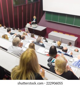 Lecturer At University. Healthcare Expert Giving A Talk To Medical Faculty Professors. Participants Listening To Lecture And Making Notes.