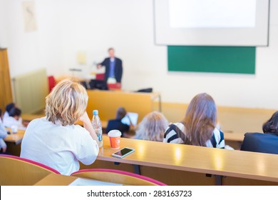 Lecturer At University. Healthcare Expert Giving A Talk To Medical Faculty Professors. Participants Listening To Lecture And Making Notes.