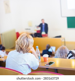 Lecturer At University. Healthcare Expert Giving A Talk To Medical Faculty Professors. Participants Listening To Lecture And Making Notes.