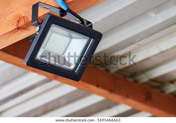 LED flood light, spot light on the\
top of the roof. Powerful construction lighting floodlight a\
lantern for illumination of a local area at\
night