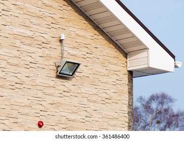 LED Floodlight On Wall Of House Covered With Lite Brown Decorative Slate Stone Surface. 