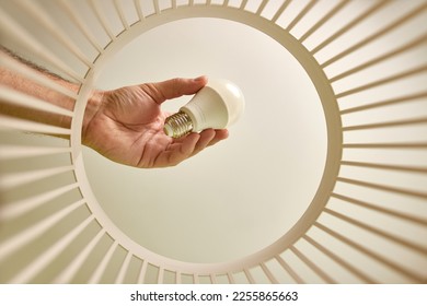 The LED lamp is thrown into the trash for disposal and recycling. View from below. The concept of disposal and processing of waste. - Shutterstock ID 2255865663