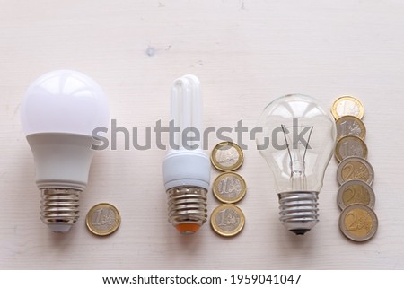 LED light bulb, incandescent light bulb, fluorescent light bulb, with coins next to it. Costs and consumption of the various types of light bulbs. 