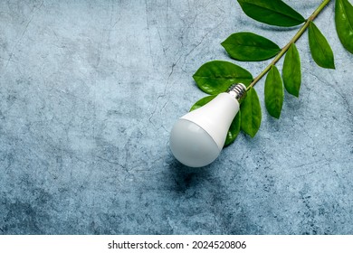 LED light bulb on a background of green leaves, as a symbol of green energy, energy saving and environmental care
