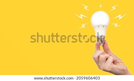 LED light bulb on orange background. Frosted white light bulb in hand. Concept - sale of LED lamps. LED light bulb with zipper around. It symbolizes electric diode lighting. Energy saving concept