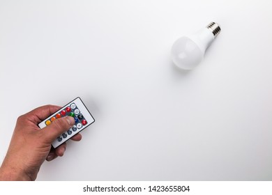 Led light bulb and remote pointing straight at it held by male hand on white background . for energy savings advertisement.