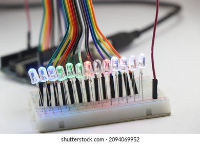 LED lights emitting multiple colors connected in a parallel circuit on a breadboard controlled by micro controller connected with jumper wires