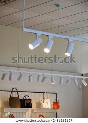 LED lights spotlight array illuminating a fashion clothing store, highlighting a display of diverse leather bags, creating an elegant and well-lit shopping environment