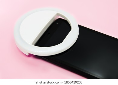 LED Selfie Circular Ring Light Lamp On Smartphone On Pastel Pink Background. Clip-on Flash Light Camera Phone For Taking Selfie Photos. Compact Device For Bloggers And Vloggers. Selective Focus