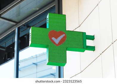 LED sign bracket in the shape of a green cross with a red heart in the center. Pharmaceutical sign symbol - Powered by Shutterstock