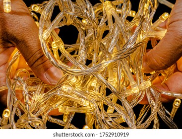 Led string lights on a black background and being held by hands. Colour Yellow. Christmas Lights,