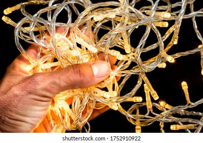 Led string lights on a black background and being held by hands. Colour Yellow. Christmas Lights,
