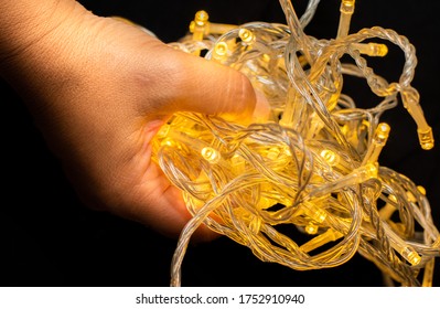 Led string lights on a black background and being held by hands. Colour Yellow. Christmas Lights,