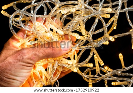 Led string lights on a black background and being held by hands. Colour Yellow. Christmas Lights,