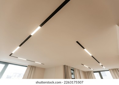 LED strip light and illumination. Also called ribbon light or LED tape to suspended on ceiling in plasterboard in empty living room include down light, white wall. Interior home design and technology
