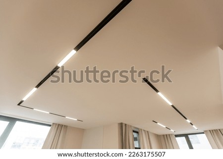LED strip light and illumination. Also called ribbon light or LED tape to suspended on ceiling in plasterboard in empty living room include down light, white wall. Interior home design and technology
