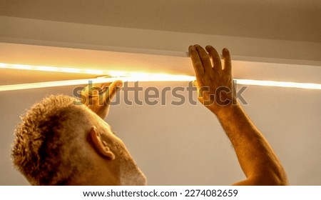 Led strip with yellow warm light, light installation. Male installer.