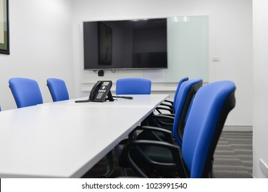 LED TV Installed To The White Wall Of The Meeting Room With Black Ip Phone On The Table