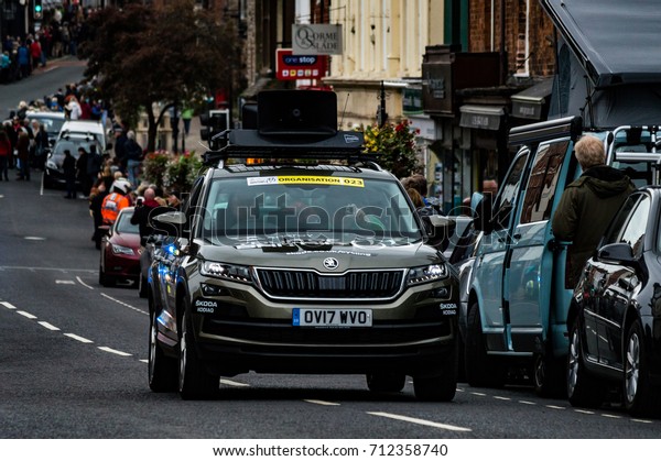 LEDBURY -  SEPTEMBER 10: The lead car announces the\
arrival of the pack, excited crowds line The Homend waiting for the\
racers to pass through the Herefordshire town of Ledbury on\
September 10th 2017