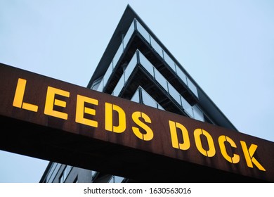 LEEDS, UNITED KINGDOM - Jan 11, 2020: Horizontal shot of a Leeds dock sign lite up on a cloudy dusk night with a block of flats behind