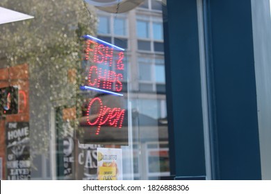 LEEDS, WEST YORKSHIRE / UK - SEPTEMBER 30TH 2020: Neon open sign in British fish and chips shop window with reflections. 