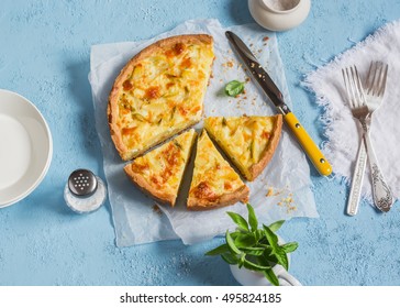 Leek, potato and cheese pie on a blue background, top view.