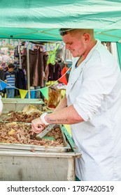 LEEK STAFFORDSHIRE ENGLAND - 26th July 2014 - Leek & District Show. Young Man Sweating On Very Hot Summers Day Carving Beef Meat At Outdoor Food Stall To Serve To Tiurists.