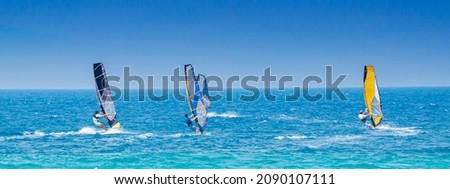 Lefkada, Greece. August 18th, 2011. Some people windsurf in the bay of Agios Ioannis in Lefkada, Greece, in an emerald green sea and with a clear sky. Banner header horizontal.