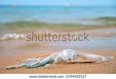 Left behind plastic bag garbage on sandy beach. Empty used dirty litter on sea shore. Environmental pollution. Ecological problem
