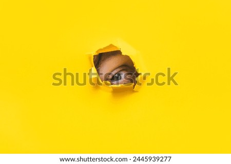Left eye looking through a hole in a yellow paper. Voyeurism. The man is watching the wife. A curious look. Jealousy, spying on or overhearing the concept. Copy space. Stock fotó © 