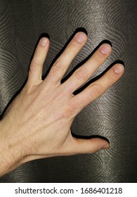 Left hand, adult male, facing downwards, showing back of hand, isolated on black background. Asian man's hand, fingers spread, palm down, dorsal view, lying on black surface. Closeup, top view.