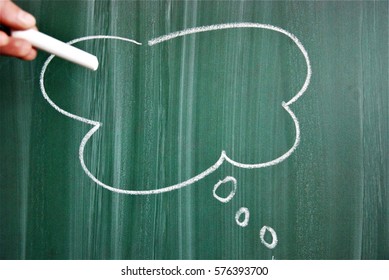 Left hand with chalk and empty cloud on the blackboard