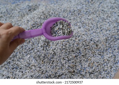 Left hand of child holding Small purple plastic toy shovel scoop out small artificial pebbles from the floor in the playground.