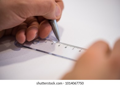 Left hand drawing with a pen while the right hand holds the ruler on a piece of paper