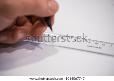 Left hand drawing with a pen while the right hand holds the ruler on a piece of paper