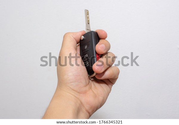 \
\
Left hand holding electronic car keys on\
isolated white\
background