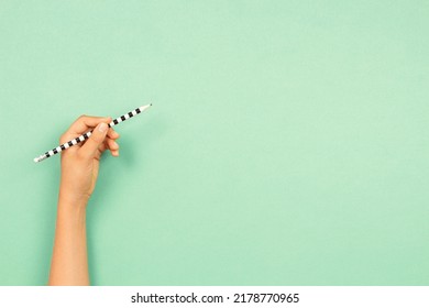 Left hand holding pencil for writing over light green background. Left Handers Day - Shutterstock ID 2178770965