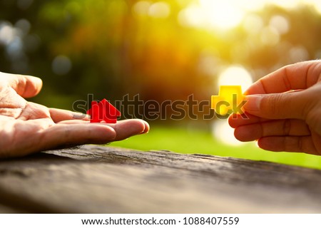 Left hand holding red and yellow model car holding.Have a solar background. Home loan with car exchange or trade in business or real estate.For family happiness.   