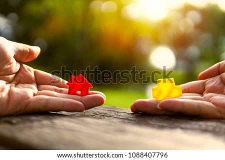 Left hand holding red and yellow model car holding.Have a solar background. Home loan with car exchange or trade in business or real estate.For family happiness.  