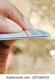 Left Hand Holding Two ID Cards On A Blurred Background