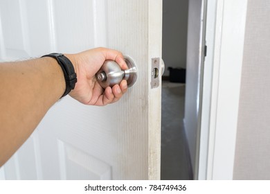 left hand of man hold and open white door to exit the room - Shutterstock ID 784749436