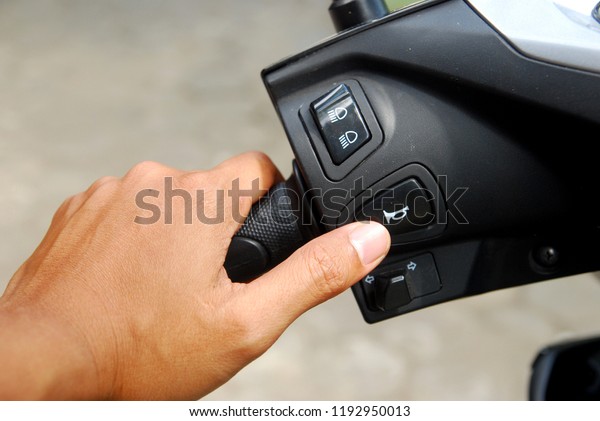 the\
left hand presses the horn button on the\
motorcycle