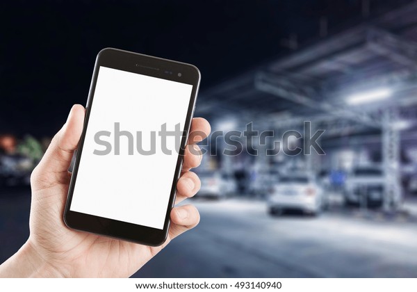 left hand using\
smartphone with blank screen on abstract blur background of outdoor\
car parking area at night 